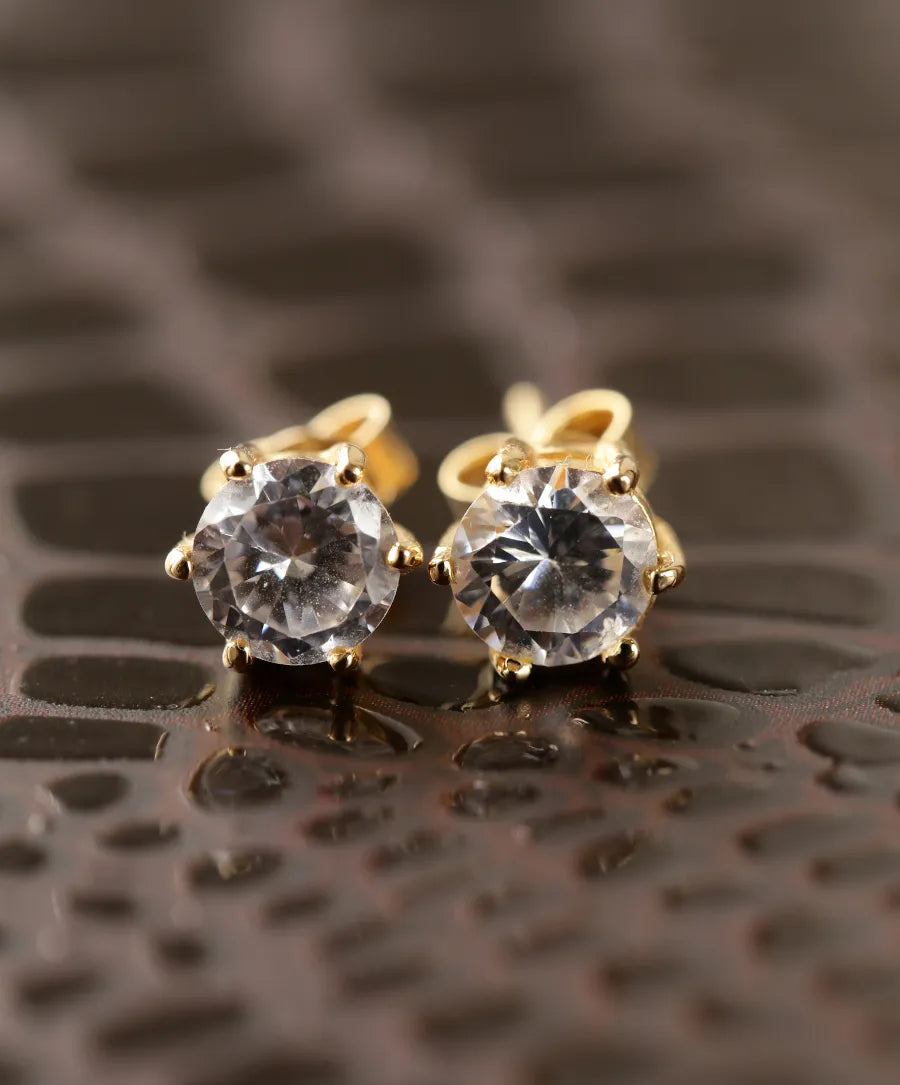 Diamond stud earrings in yellow gold on a leather surface