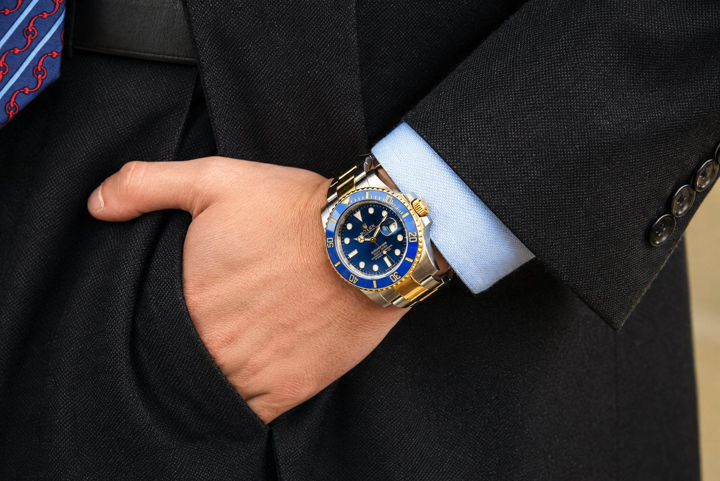Two-tone Rolex Submariner with a blue dial worn on the wrist beneath a dark suit