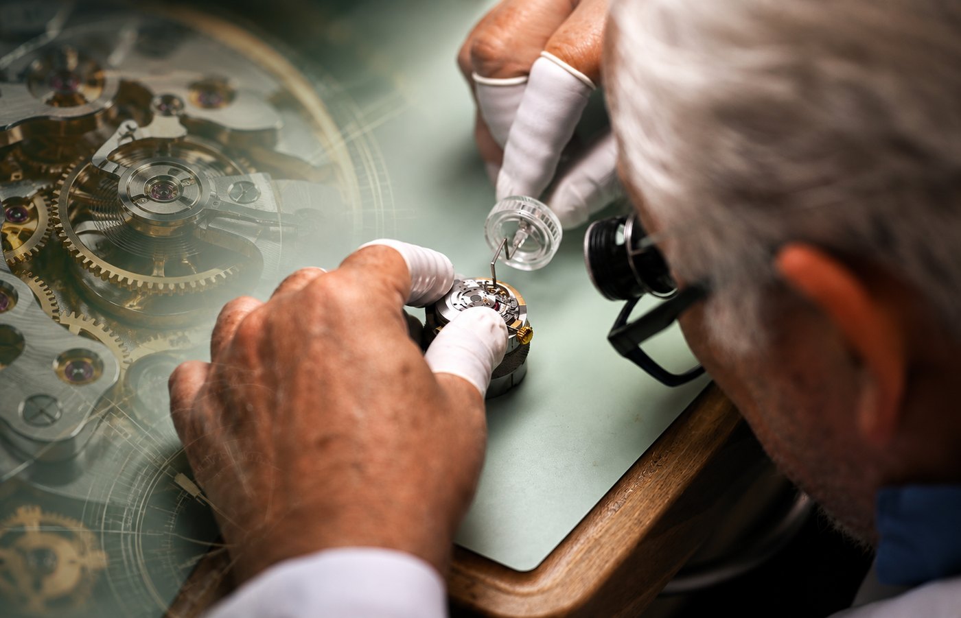 A watchmaker wearing a loupe and finger cots assembling a watch movement at the bench